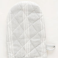 Cloud / White: A quilted oven mitt made from light grey and white striped linen.