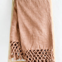 Clay: A muted red-brown cotton throw blanket with knotted open weave trim, displayed on a ladder.