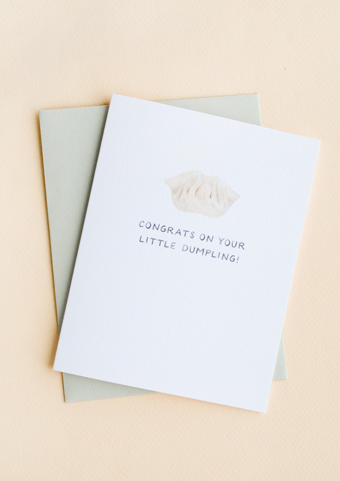 A greeting card with illustration of soup dumpling with text underneath reading "Congrats on your little dumpling!"