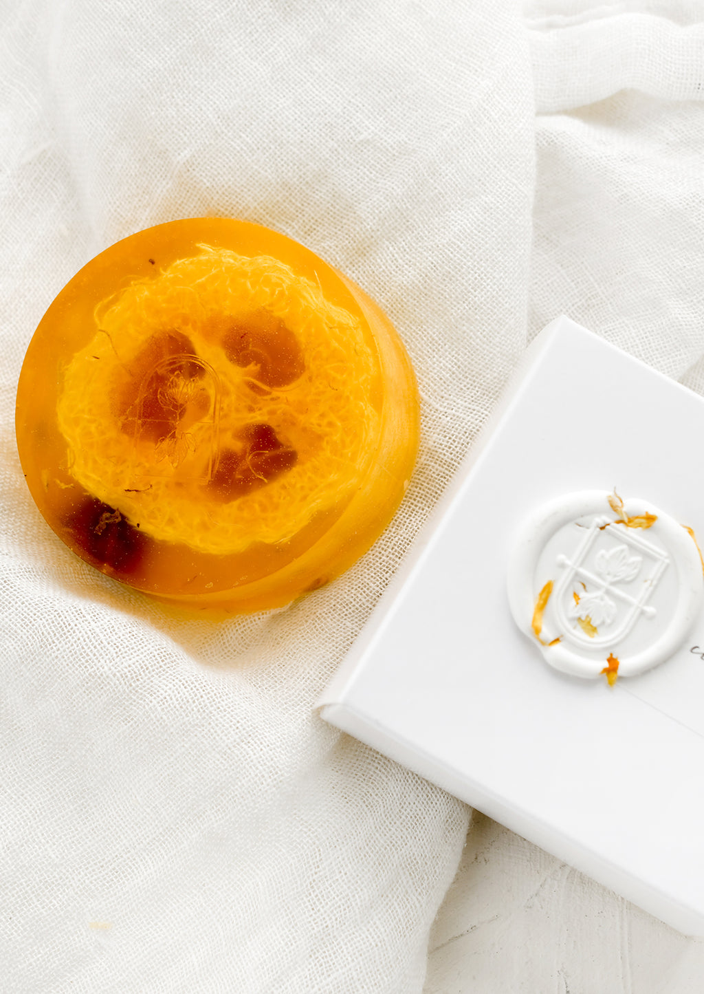 Citrus + Mint: A round translucent orange bar soap with wax seal packaging.