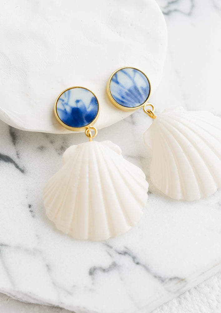 A pair of earrings made from seashells and recycled blue and white pottery.