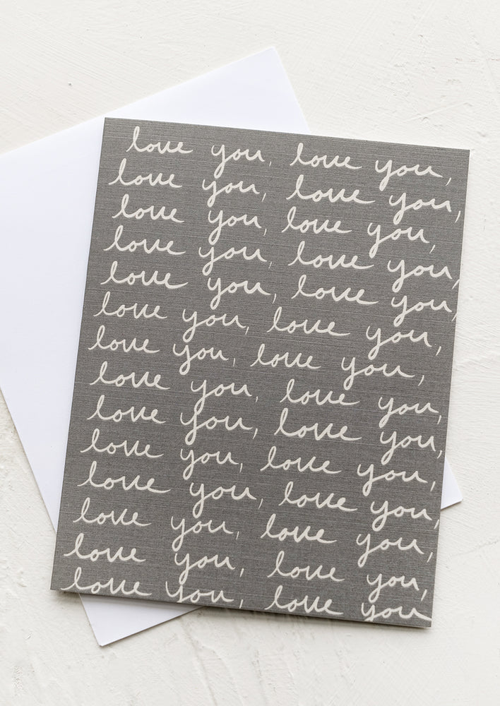 A greeting card with "love you" written in cursive over and over again.