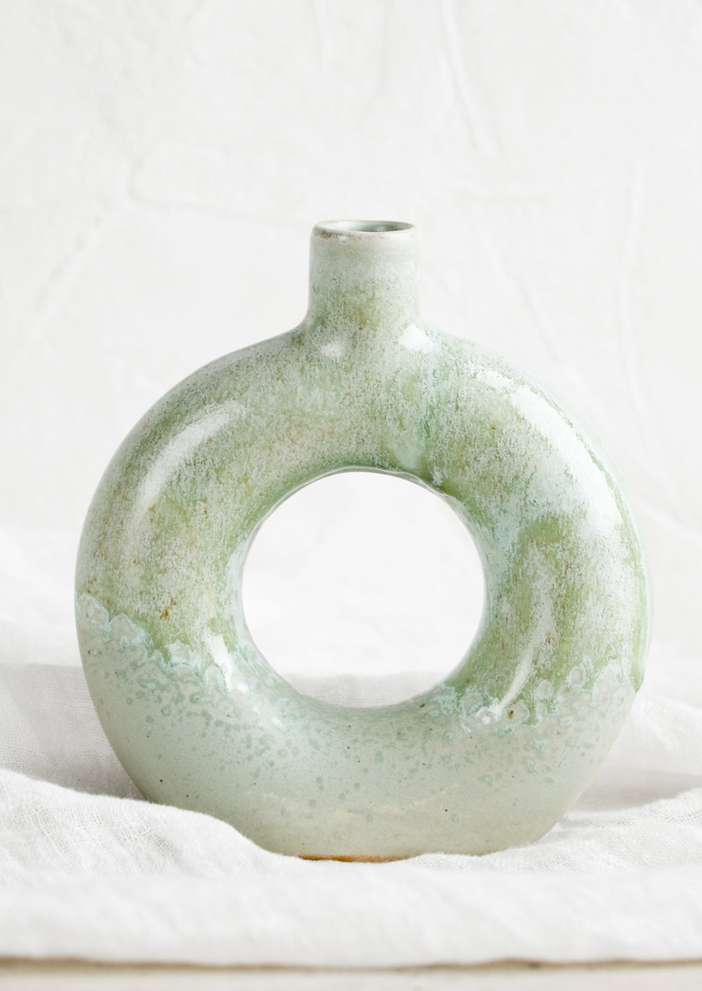 Circular: A ceramic vase in mottled aqua glaze with hollow circle shape.