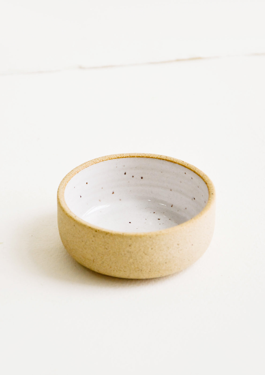 Small ceramic bowl with raw clay exterior and speckled white interior