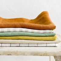 1: A stack of linen tea towels in a mix of assorted solid colors and patterns.