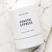 Coastal Cypress: A votive scented candle in cylinder packaging.