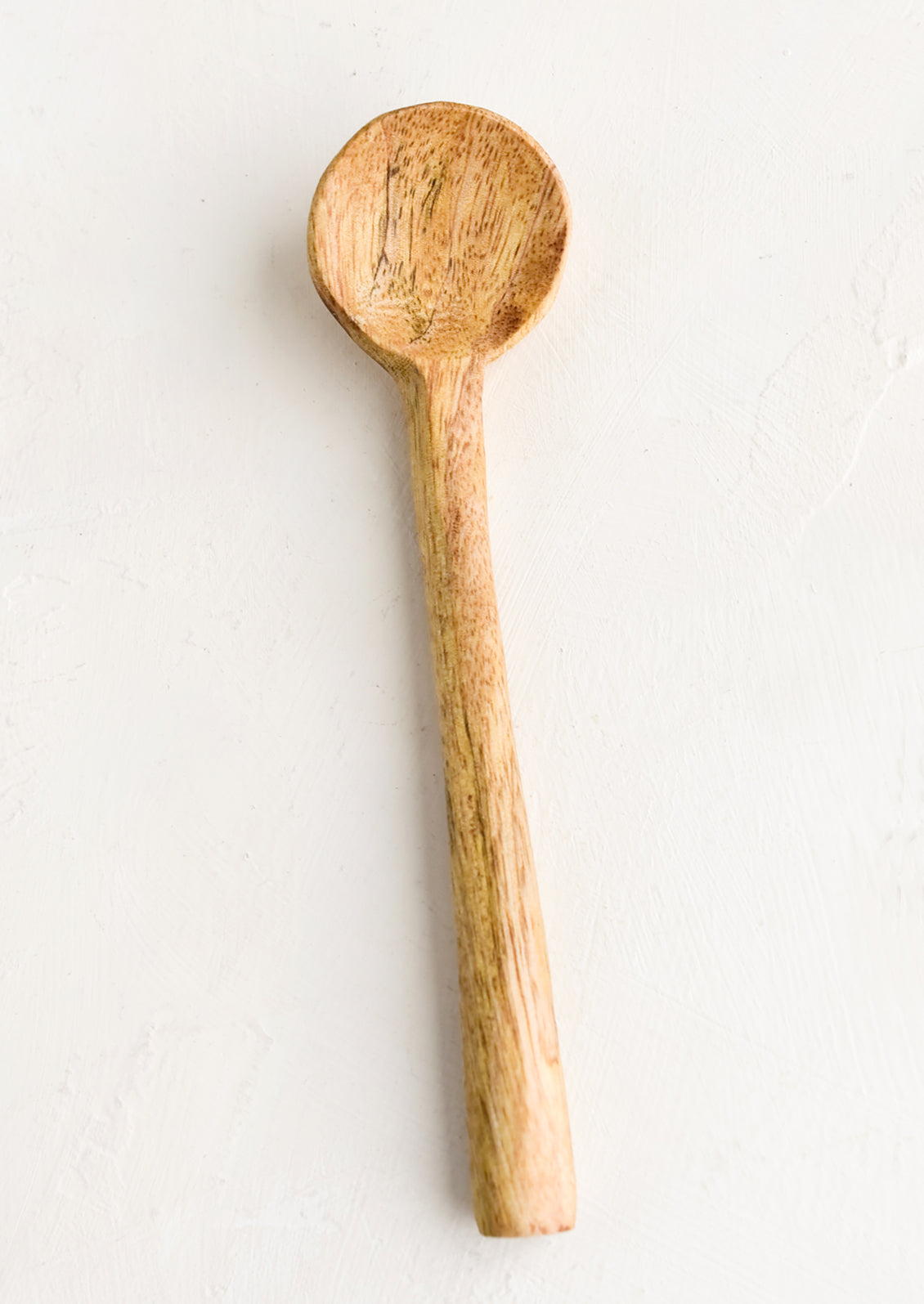 A simple carved wooden teaspoon.