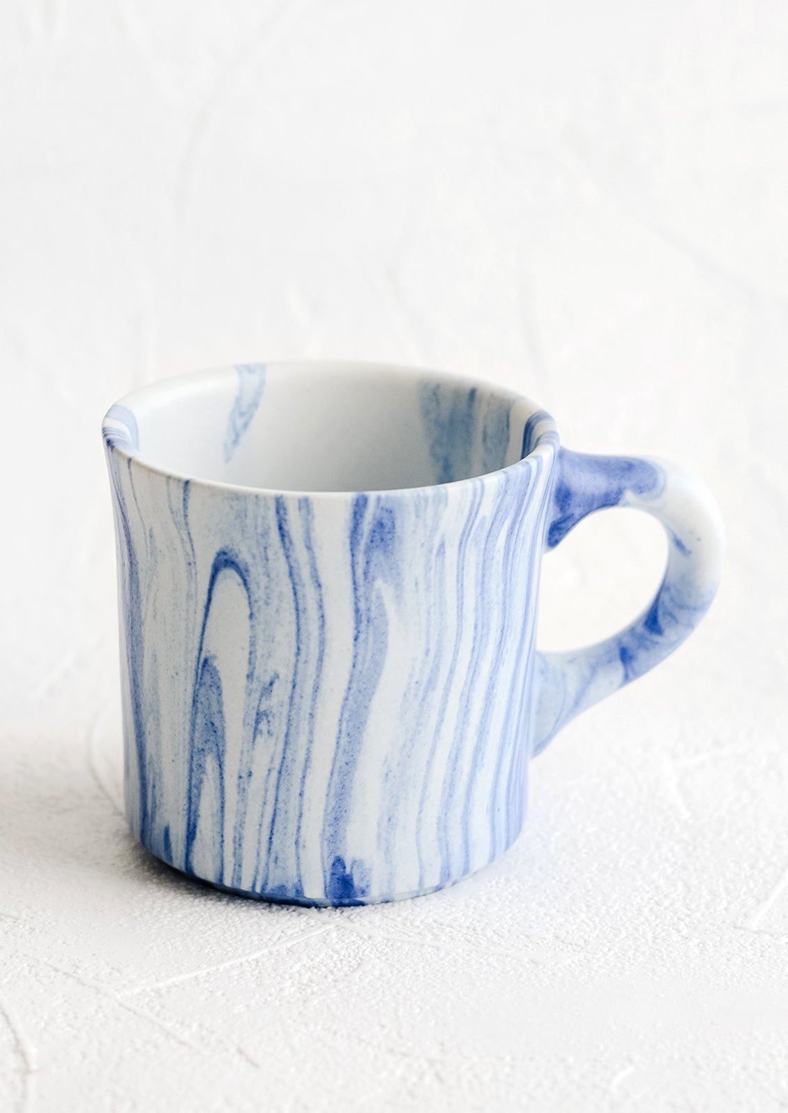 A ceramic mug in white with marbleized pattern in blue.