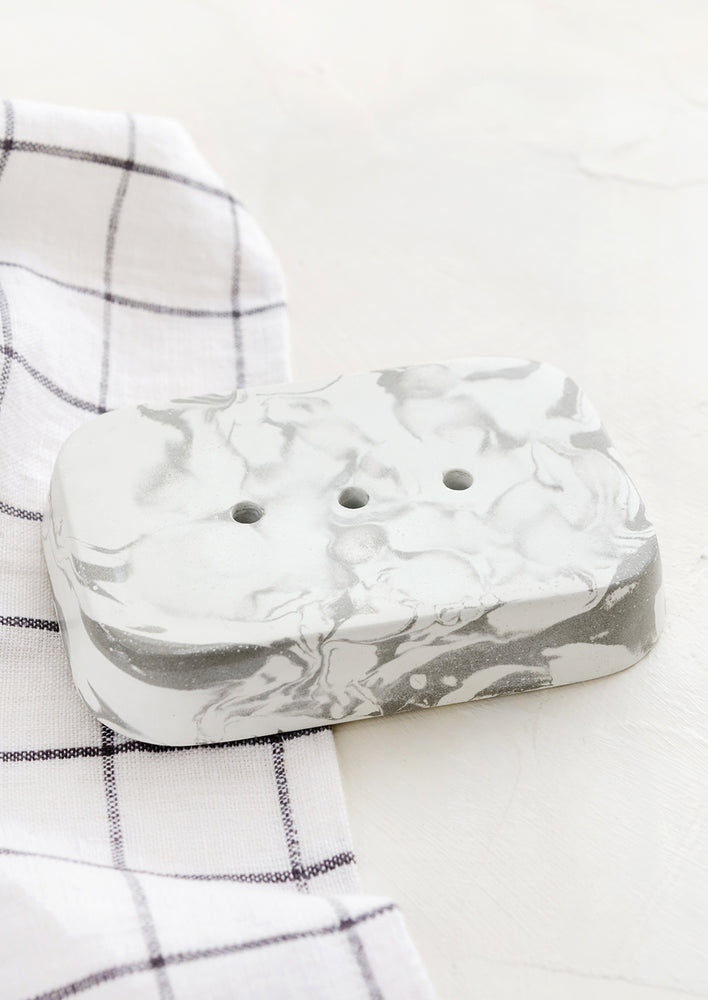 1: A rectangular soap dish in marbled white and grey concrete with three drainage holes.