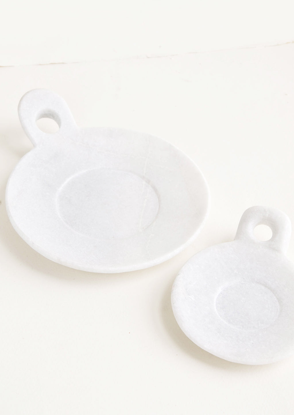 2: Round marble dishes with circular cutout side handle and circular inset at center