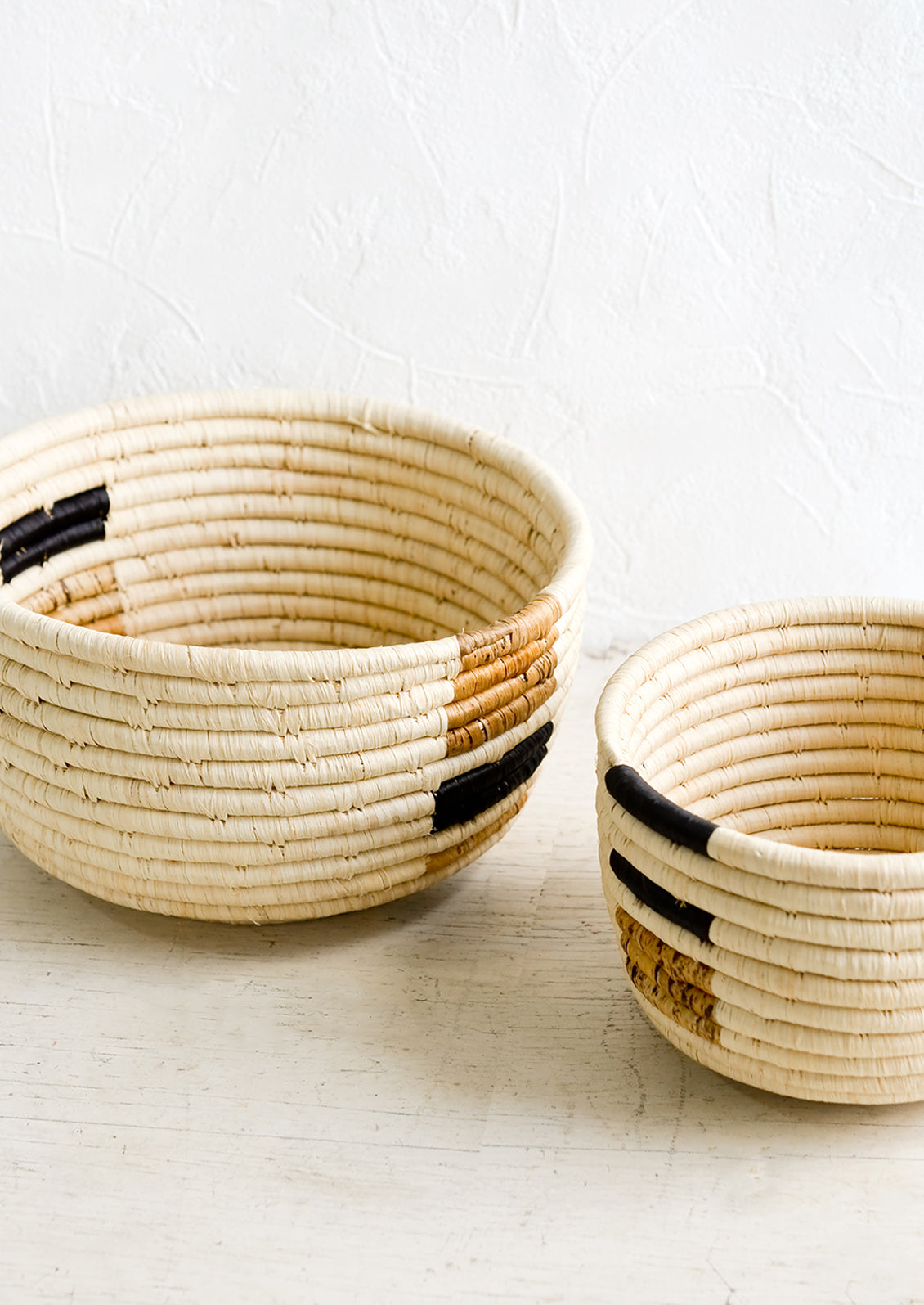 Two raffia catchall baskets in natural palette and incremental sizes.
