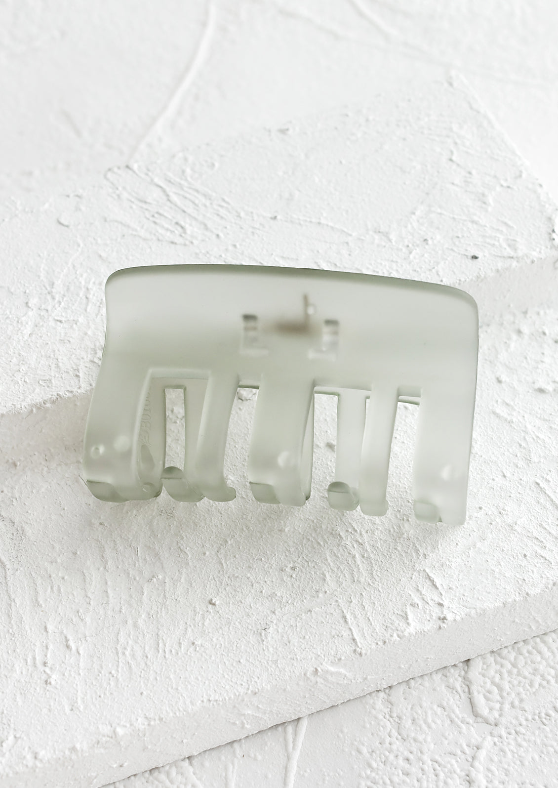 A transparent hair clip in matte sage green.