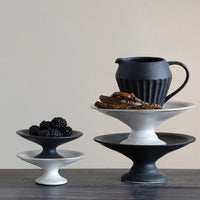 Large / Black: Ceramic pedestal risers in black and white styled with food.