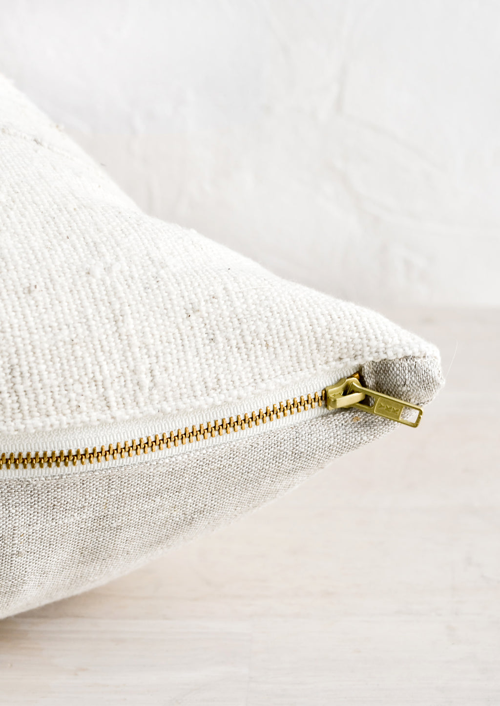 5: An exposed brass zipper on the bottom of a throw pillow.