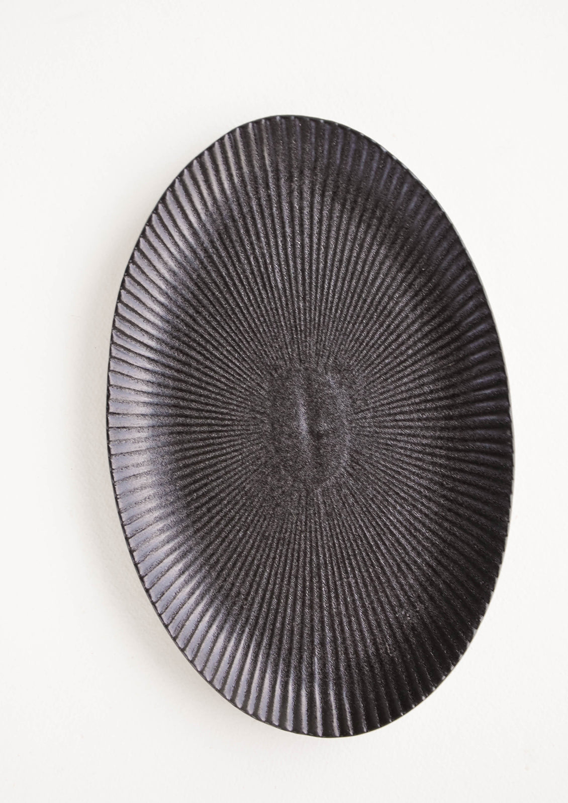 Oval-shaped, black ceramic tray with radiating lines pattern