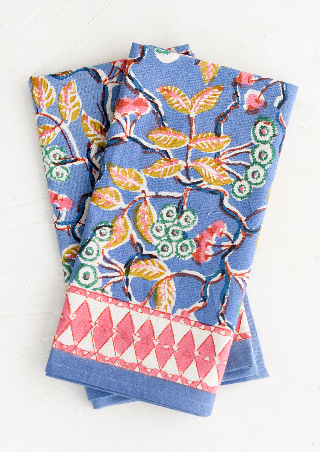 1: A folded pair of cotton napkins in blue and pink botanical print.
