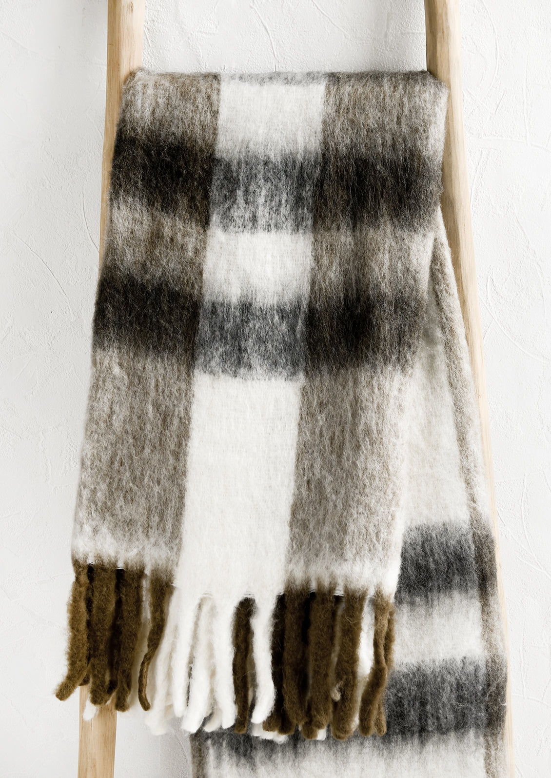 A mohair-like throw blanket in white with brown and black plaid pattern.