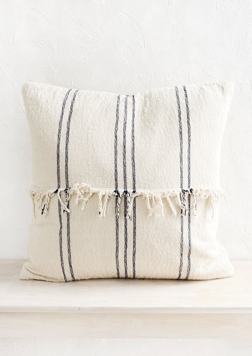1: A natural cotton throw pillow with vertical dark stripes and fringed panel at center.