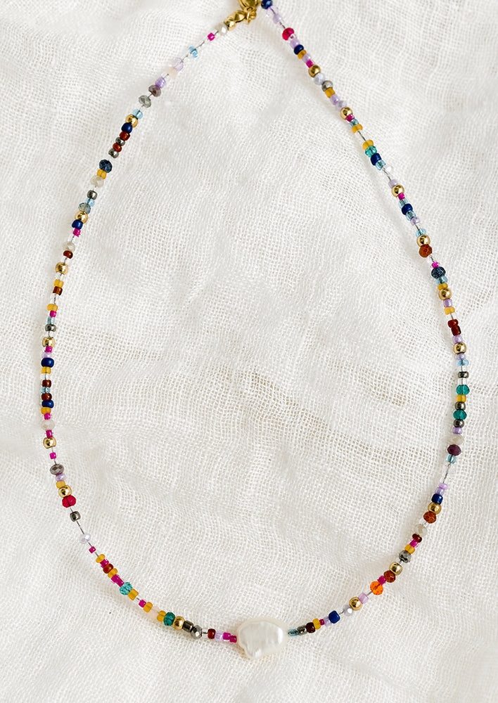 1: A multicolor seed bead necklace with single pearl at center front.