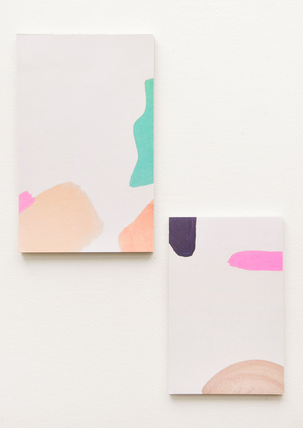3: Two notepads, decorated with colorful abstract shapes.