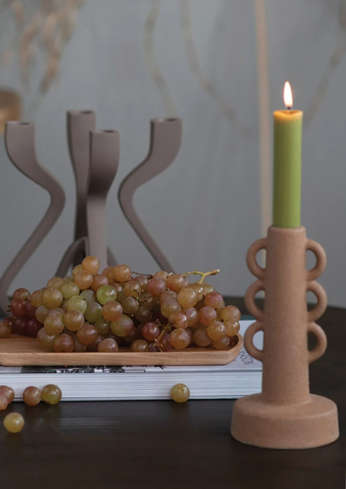 A textured sand colored taper holder with decorative loop shape.