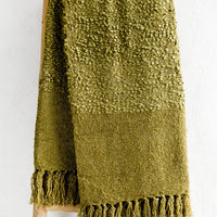 1: A moss green boucle throw with tassel trim.