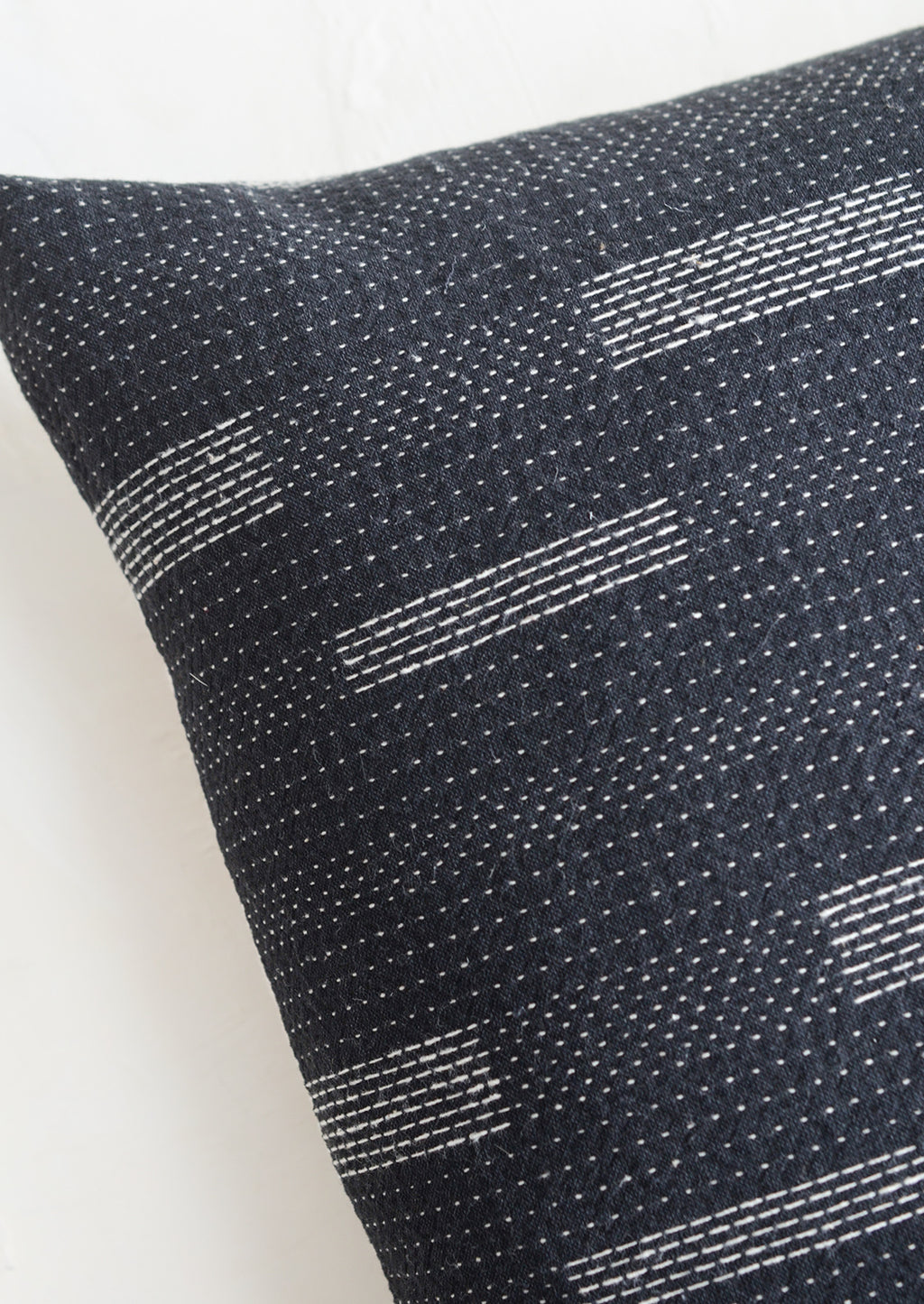 4: Square pillow in black with white variegated stitching in assorted line patterns