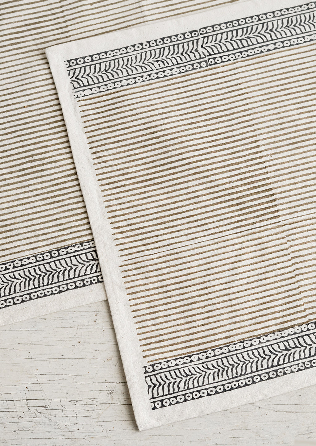 Taupe / Deep Indigo: A cotton placemat with block print design, borders at top and bottom with striped center.