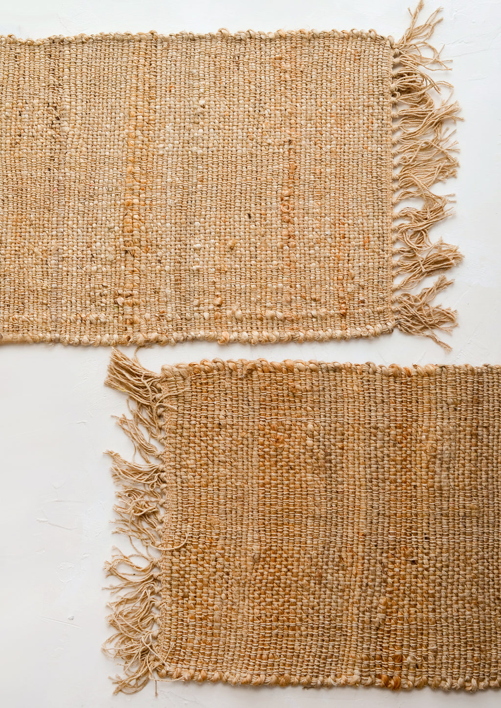 4: Two jute placemats with fringed trim.