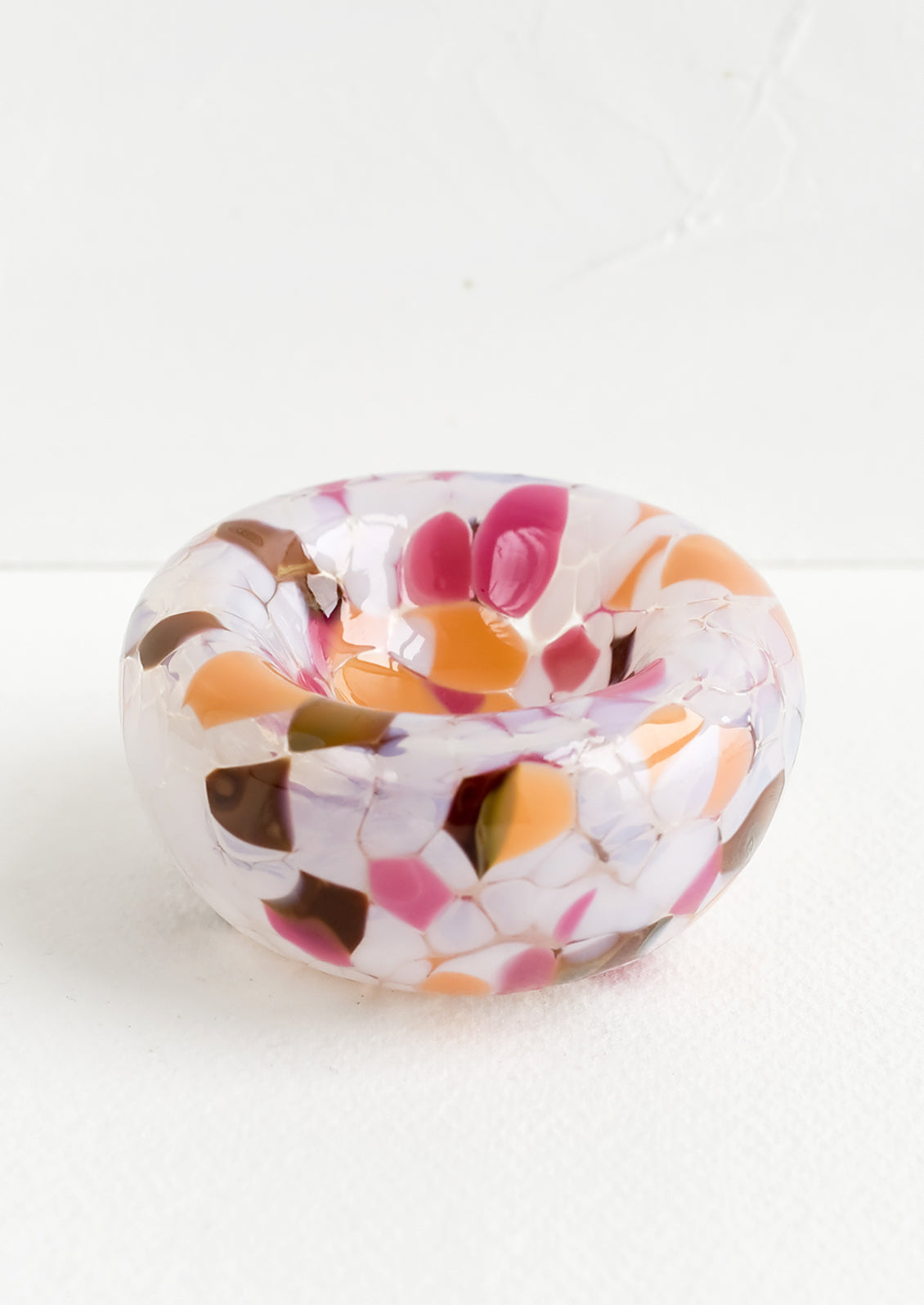 A small decorative art glass bowl in pink, orange, white and brown speckle.