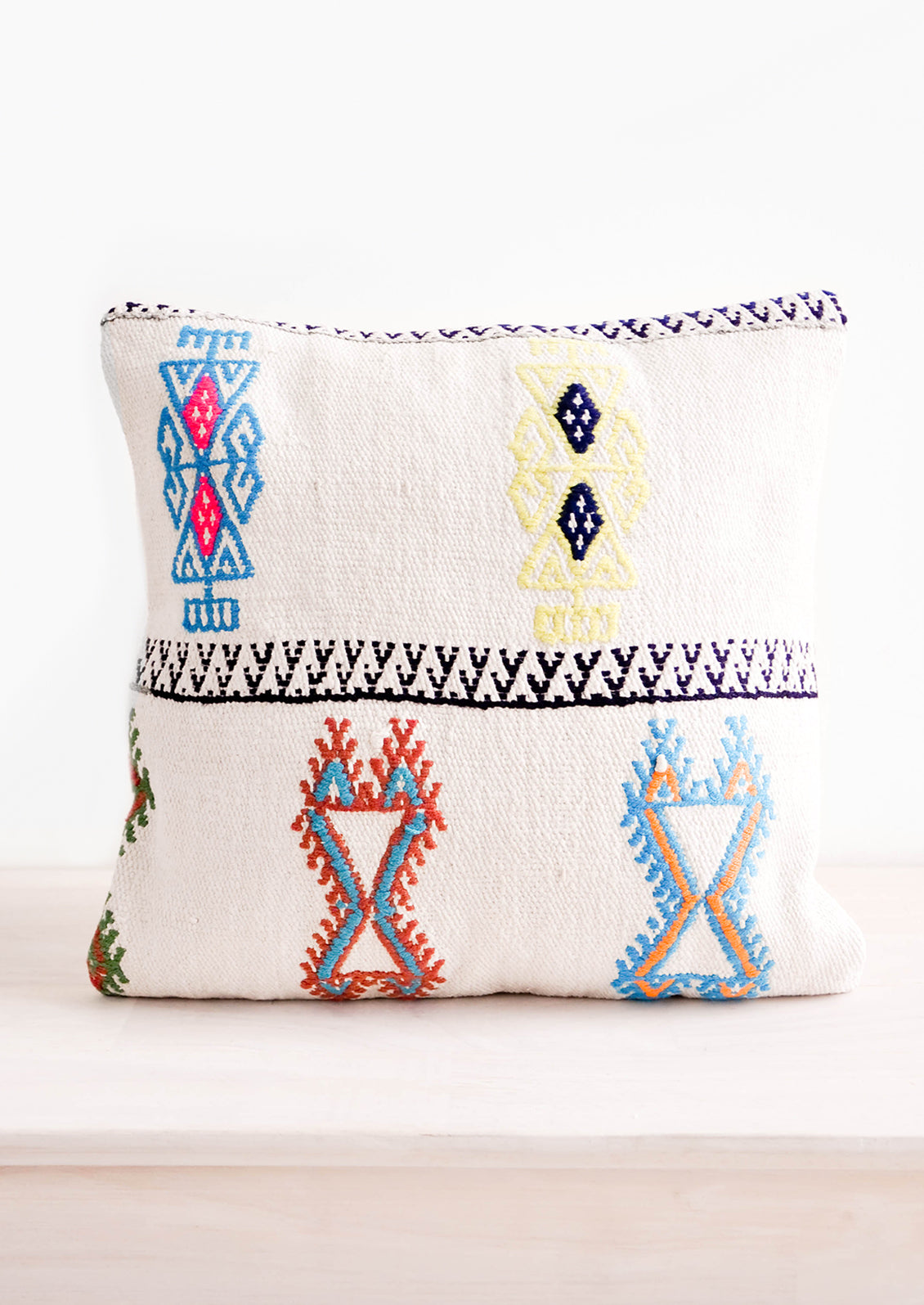 Square throw pillow with neon embroidery on ivory background