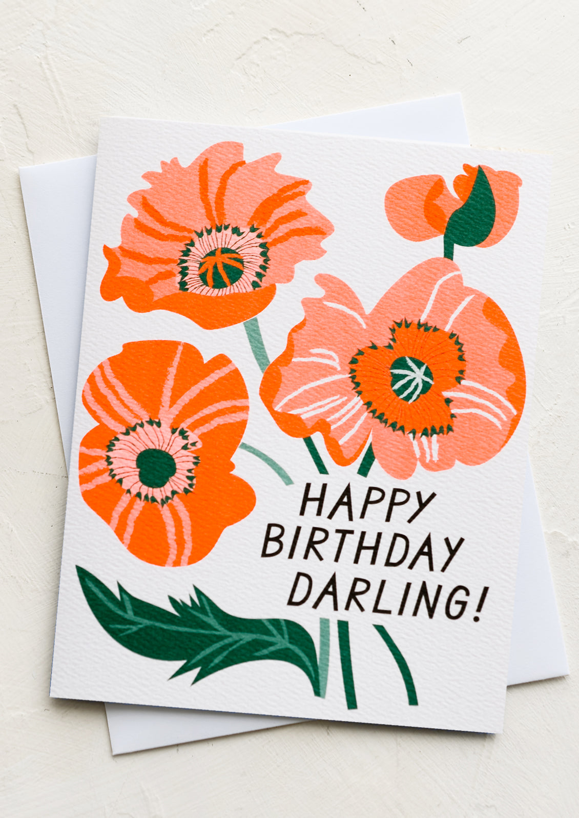 A white greeting card with neon orange poppy illustration, text reads "Happy Birthday Darling!".