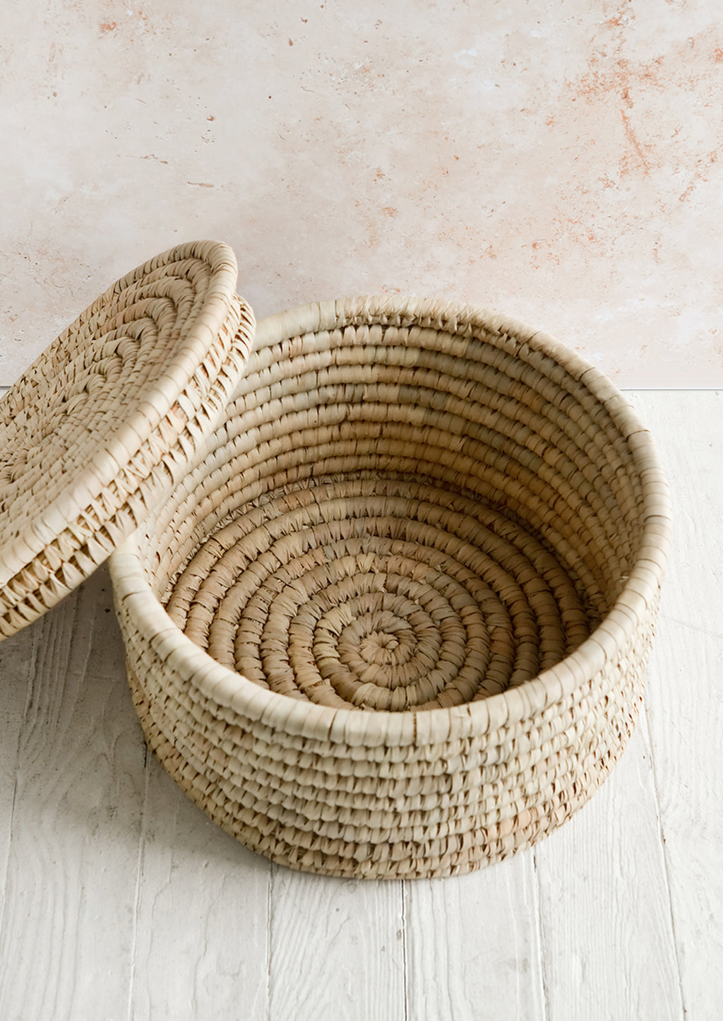 3: A round palm leaf storage basket with lid askew.