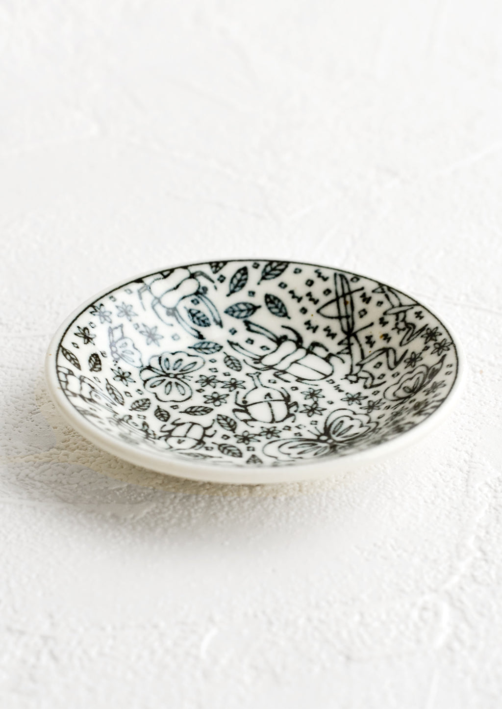 2: A round ceramic trinket dish in black and white with insect print.