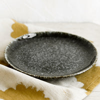 2: A round plate in glossy black speckled glaze.