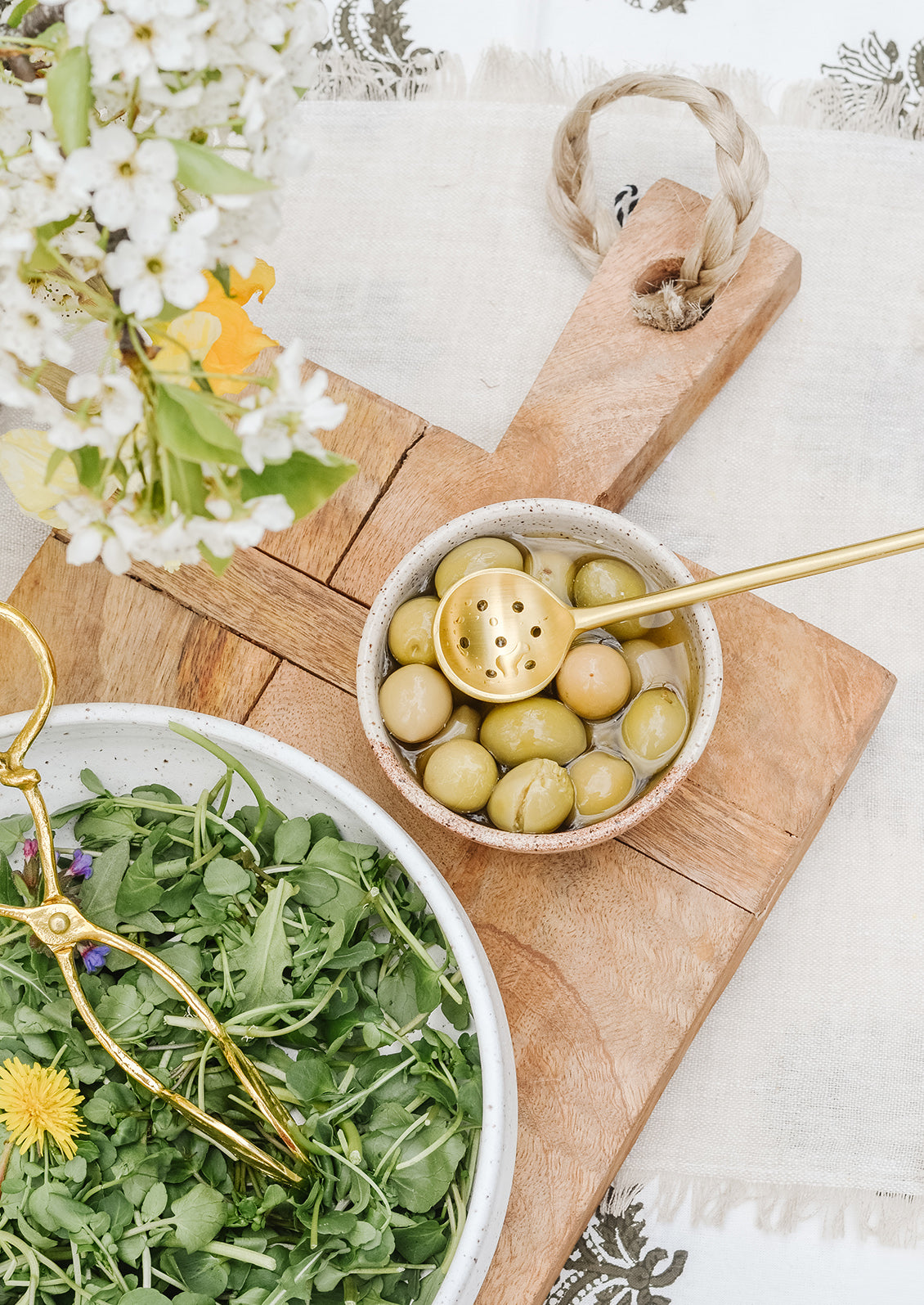 A tableware scene with salad and bowl of olives.
