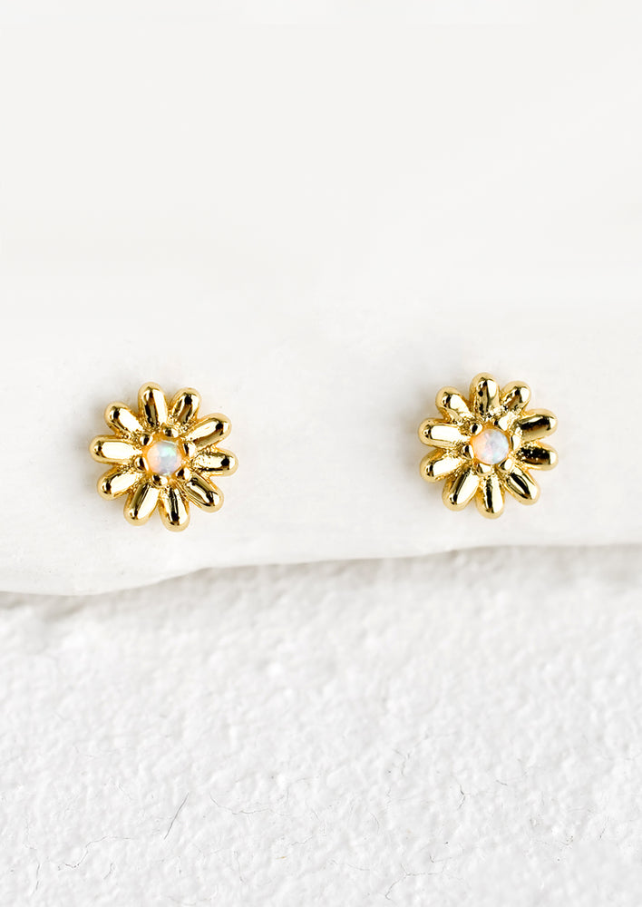 A pair of gold flower shaped stud earrings with opal centers.