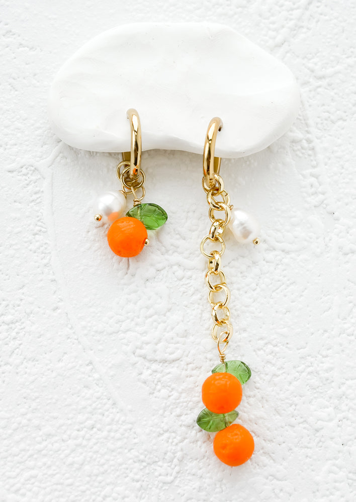 1: A pair of earrings with orange fruit beads, one short and one long.