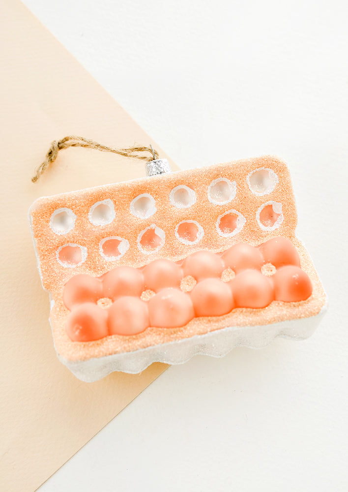 A holiday ornament designed to look like an open carton of a dozen eggs.