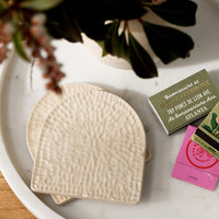 Sandstone: Cream coasters on a tray with matches.