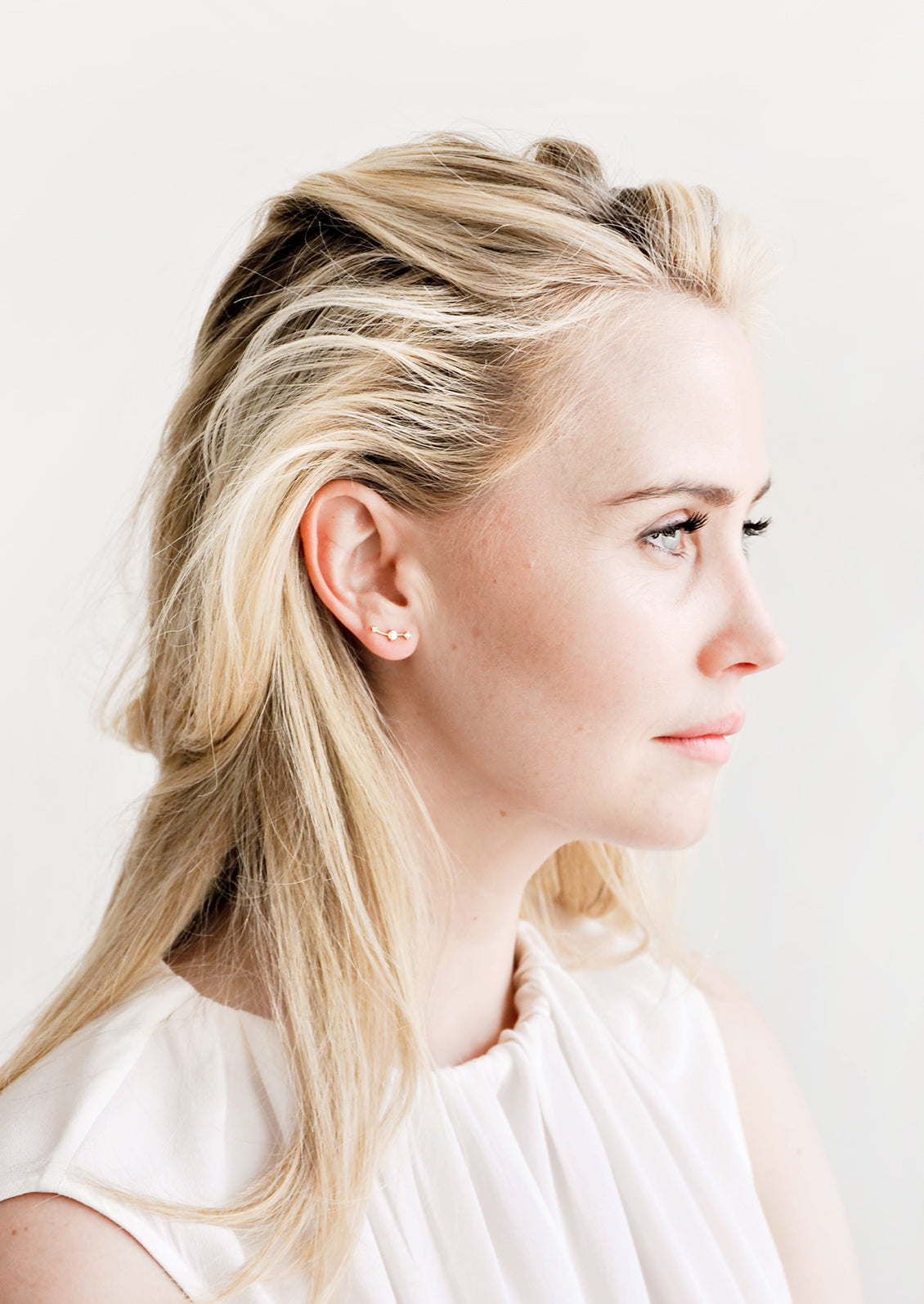 Model wearing opal and rhinestone climber-style stud earrings