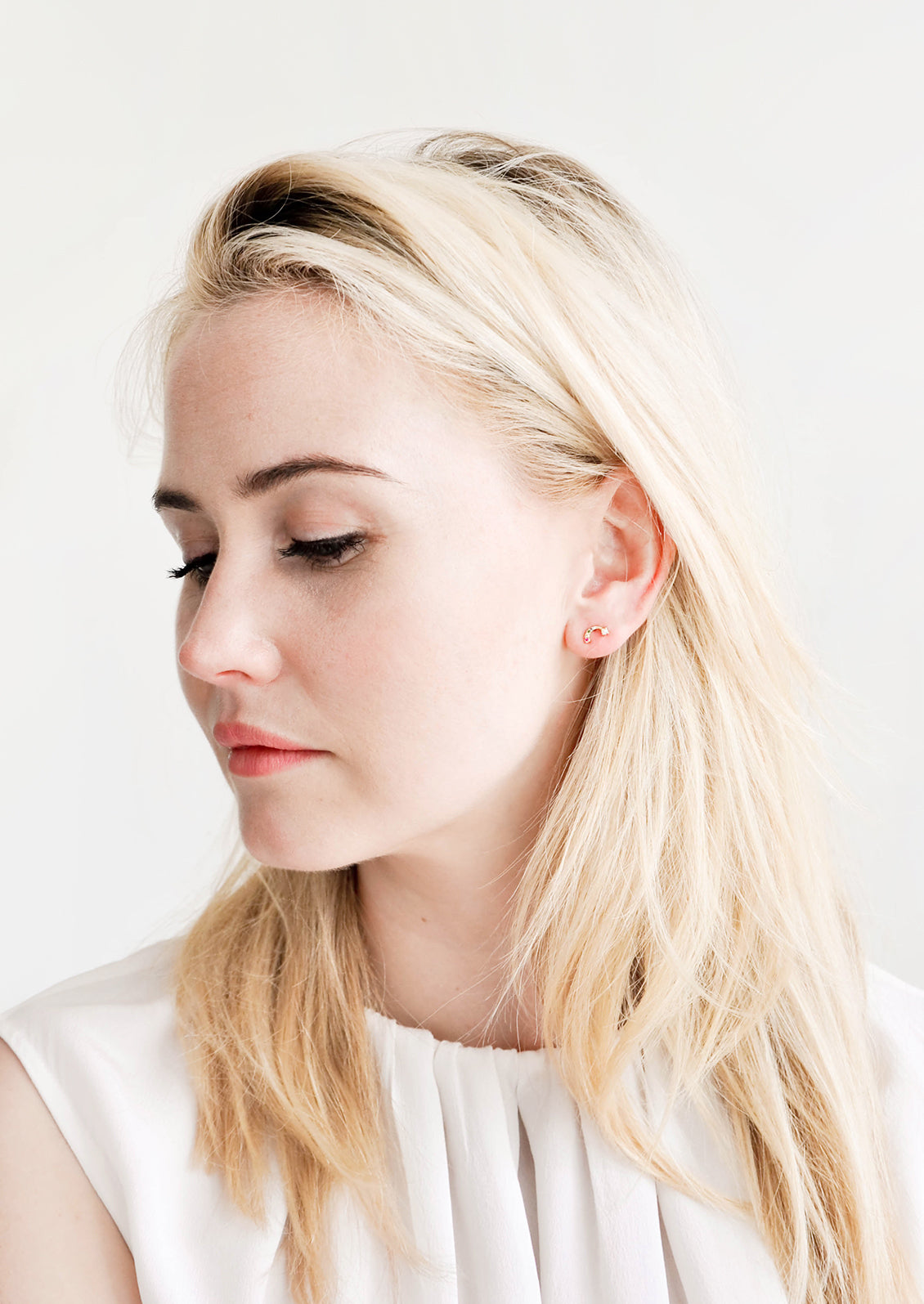 Model wearing rainbow stud earrings with colored crystals