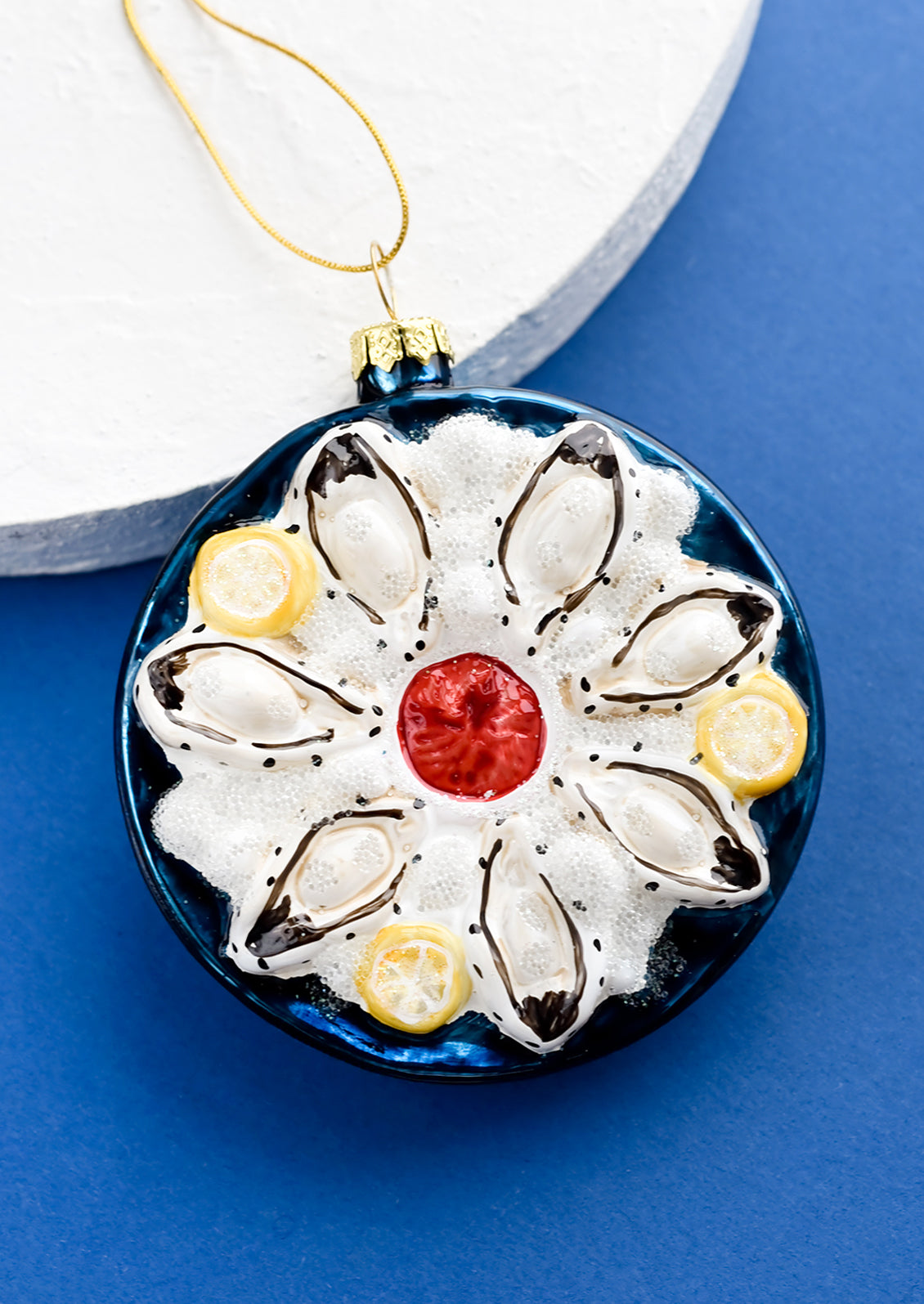 A round glass ornament in shape of oysters on a plate of ice.