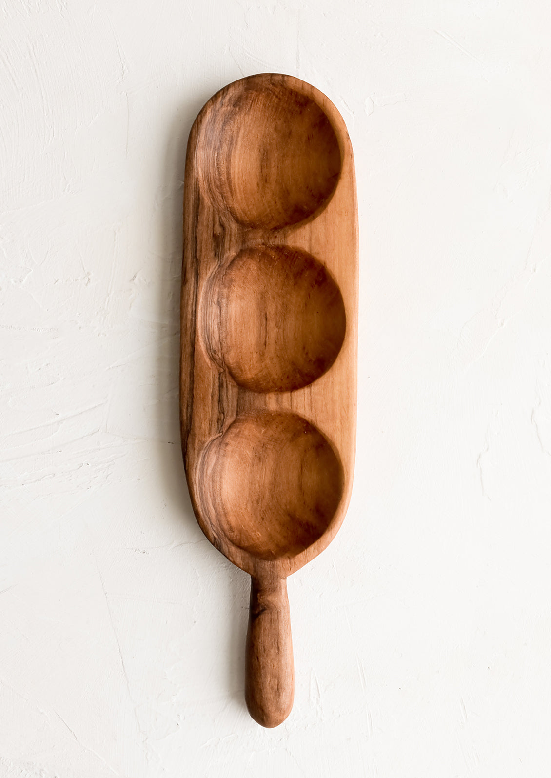 A paddle shaped wooden board with three individual wells.