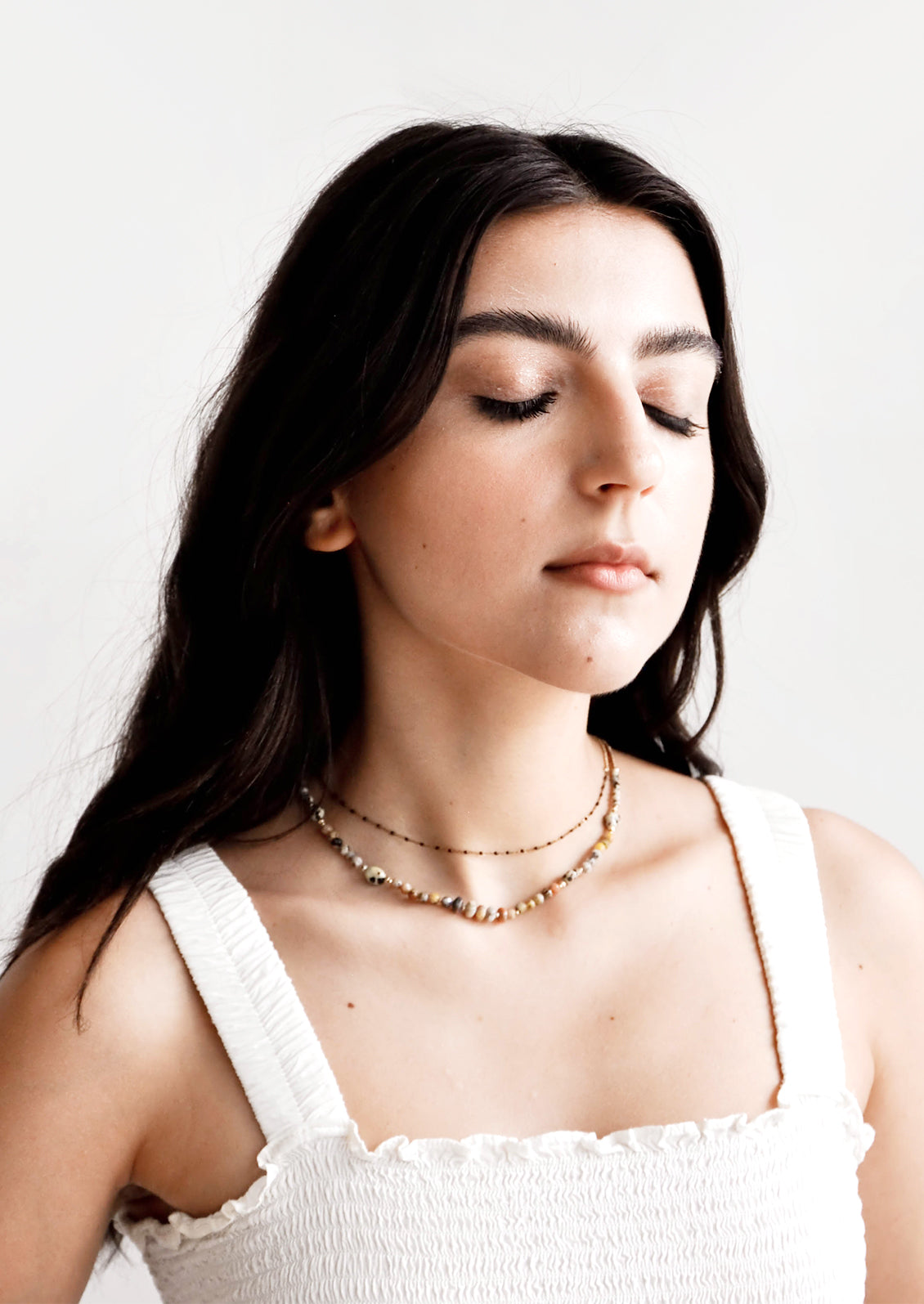 Model shot showing woman wearing necklace and white top.