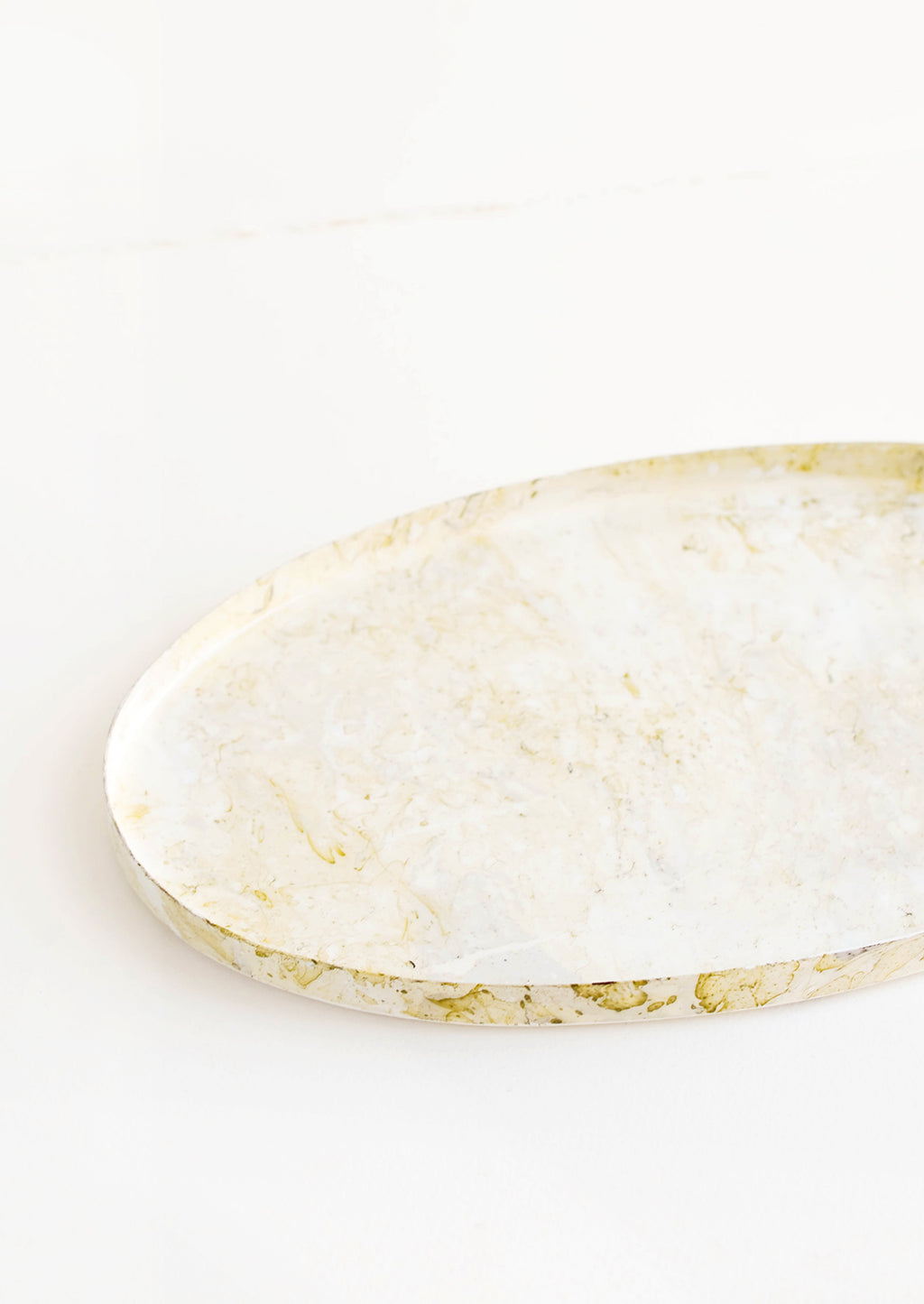 2: Alternative view of oval shaped decorative tray with lipped rim, covered in a shiny enamel finish in an off-white, marble-like pattern.