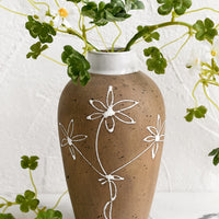 1: A brown clay vase with white floral sketch.