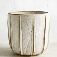 3: A tan ceramic planter with decorative raised grooves.