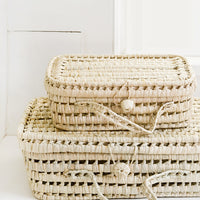 1: Baskets woven from natural palm leaf in suitcase shape, in small and large sizes.