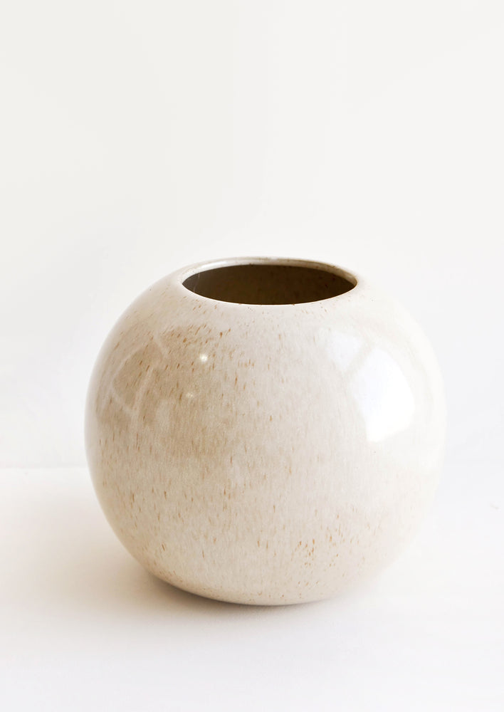 Round, spherical planter with wide opening at top. Glossy, neutral glaze with light speckles.